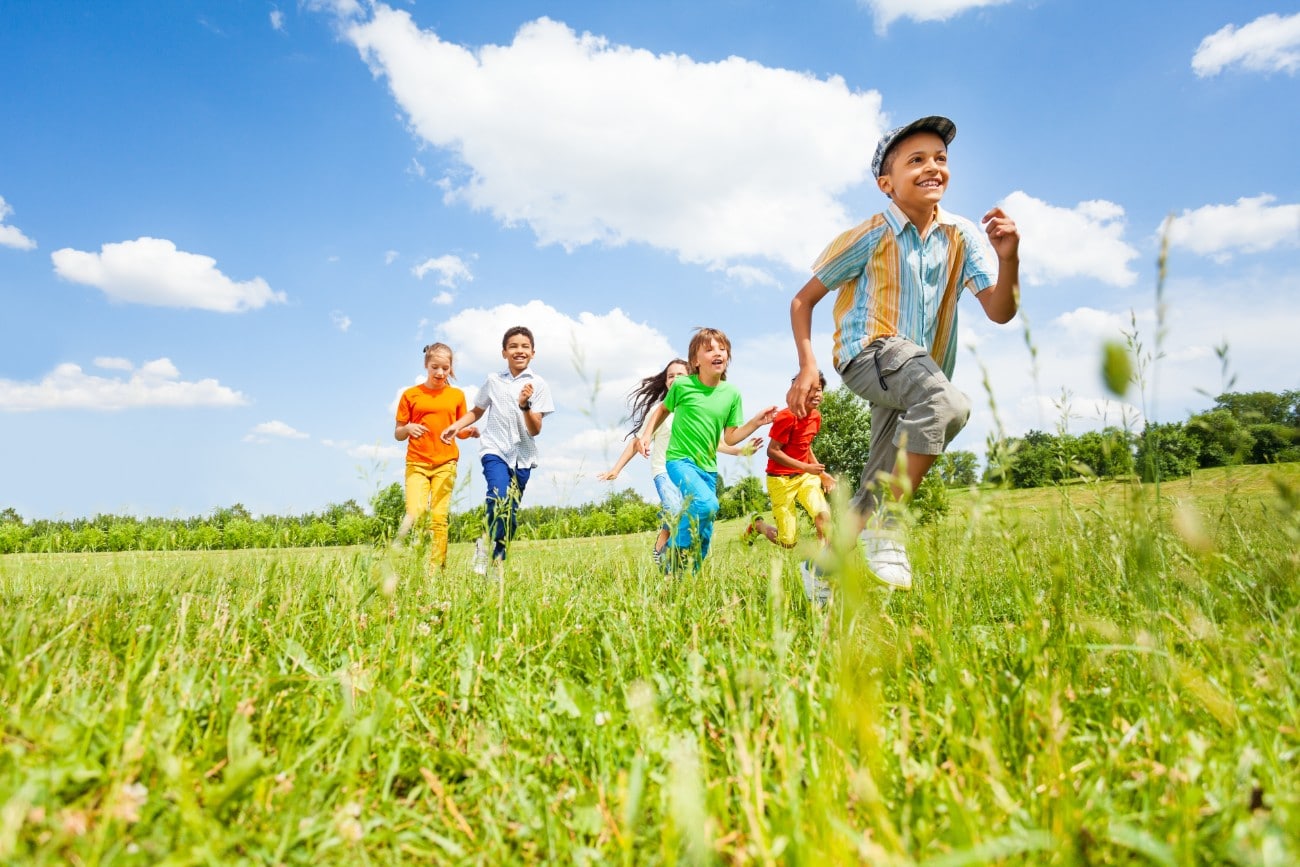 a group of children running in the grass