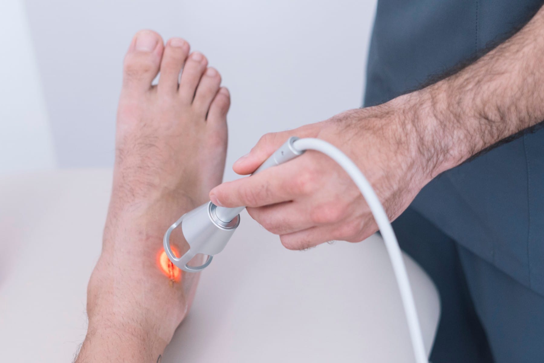 doctor performing laser therapy on a patient's foot
