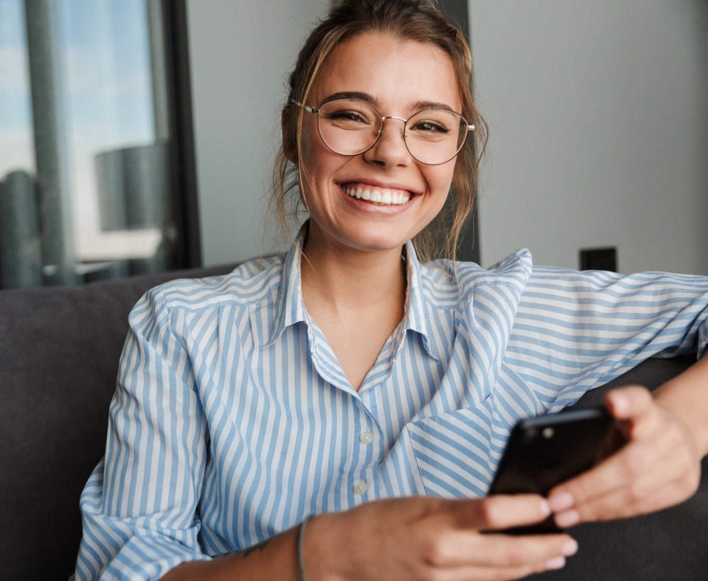 woman smiling while holding her phone